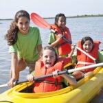 Teenage girl helping children in kayak
